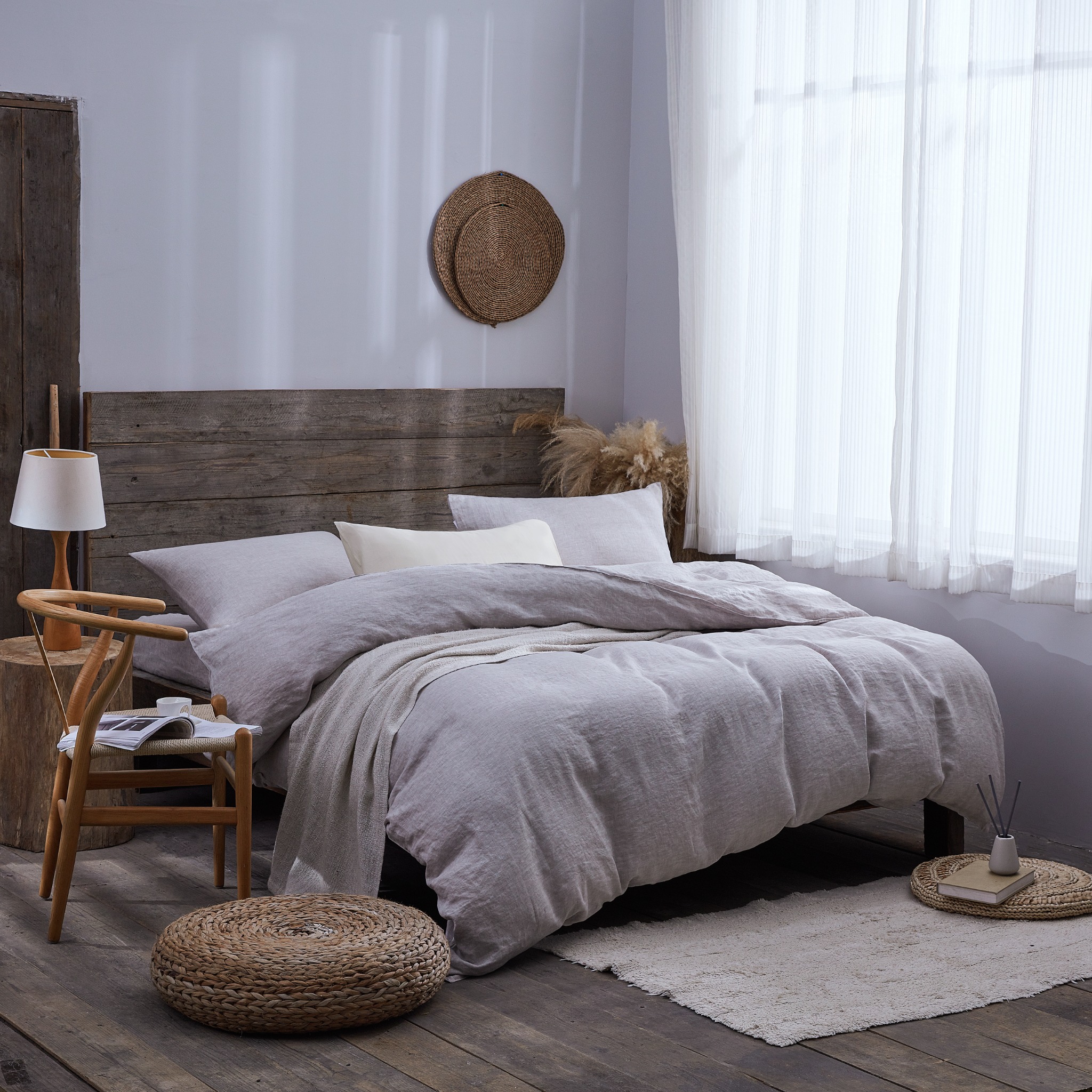 Full-size grey linen bedding in naturally lit wooden bedroom